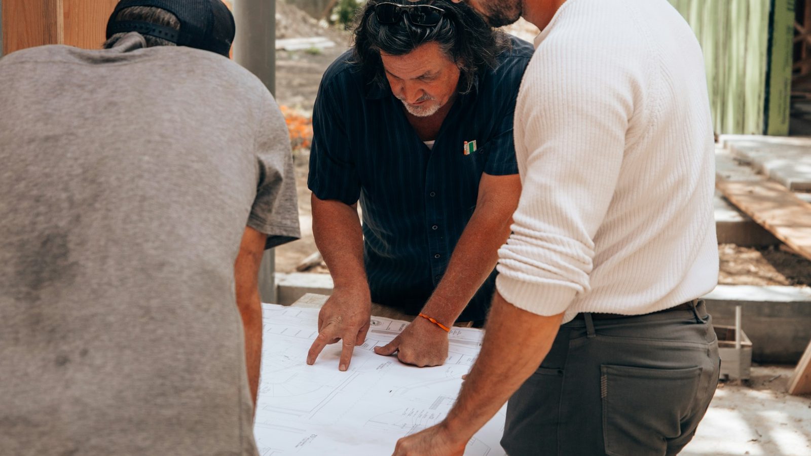 Contratista planificando la obra sobre los planos con profesionales de distintos gremios